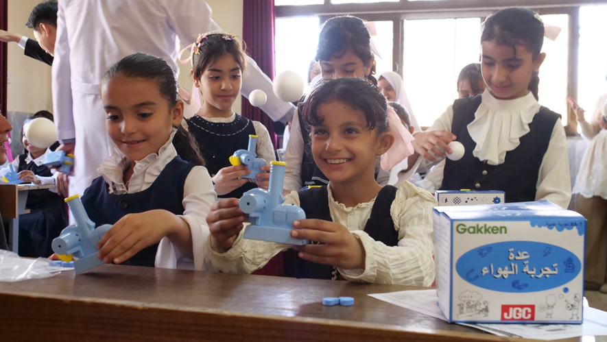 Students learning about invisible air flow using science experiment kits distributed to each student.